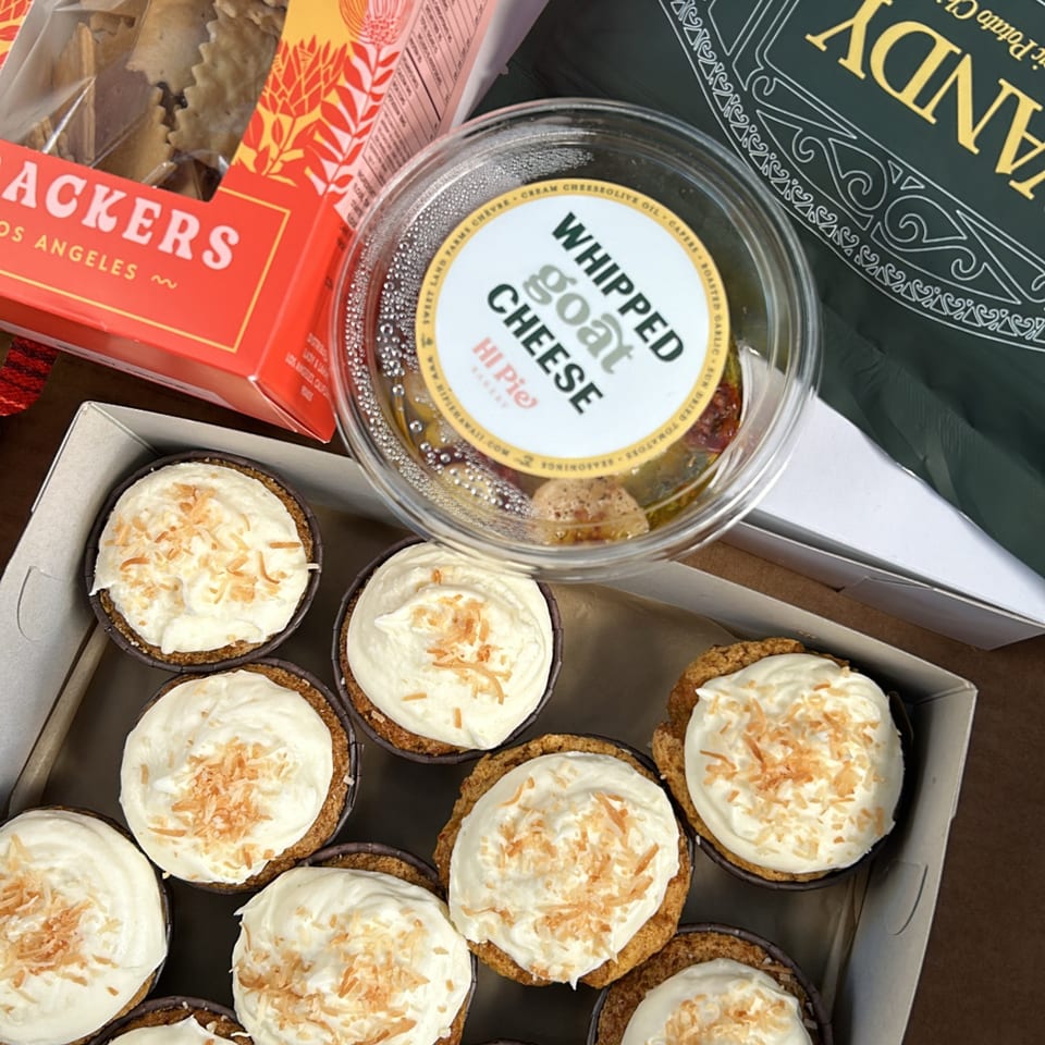 A box of HI Pie Bakery + Cafe mini pies with whipped topping and toasted coconut flakes.