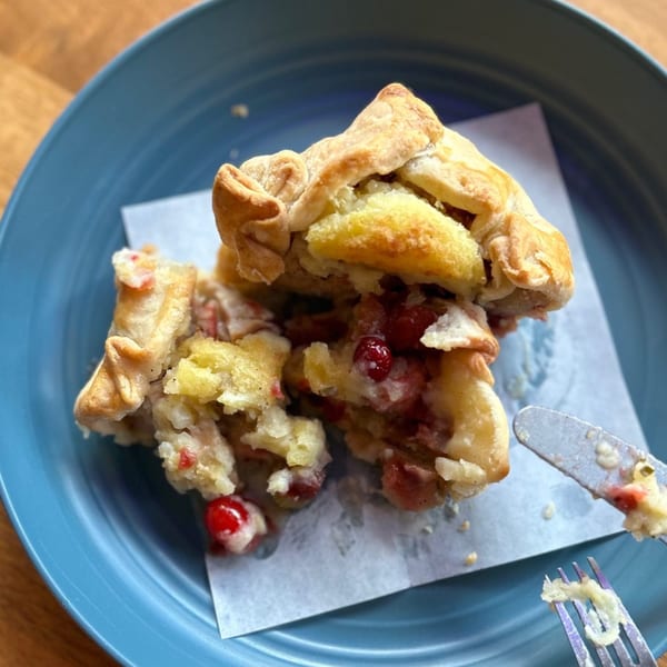 A HI Pie Bakery + Cafe cranberry pie, cut open, on a blue plate with a fork and knife.